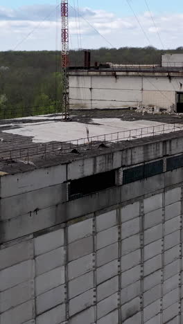 ruined large building of a factory on green nature background. old industrial plant with abandoned building. abandoned factory. vertical video