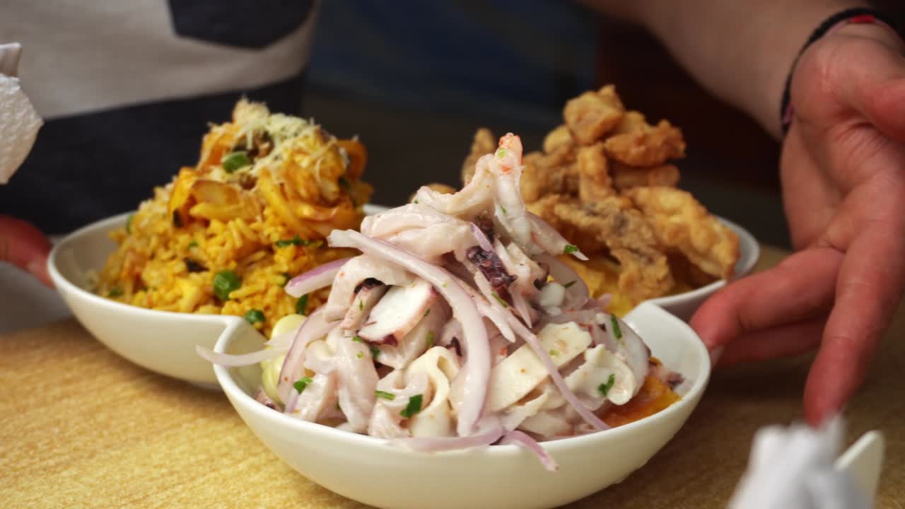 4k에서 해변에 있는 레스토랑에서 생선 치차론, 해산물 샤우파, 세비치의 해양 트리오의 클로즈업