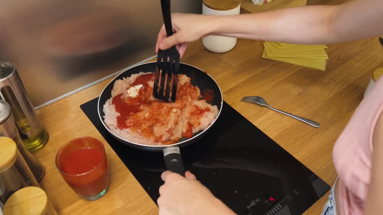 Cooking ground meat with tomato sauce in the kitchen