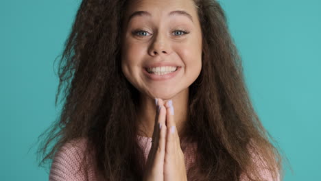 caucasian curly haired woman crossing fingers in front of the camera.