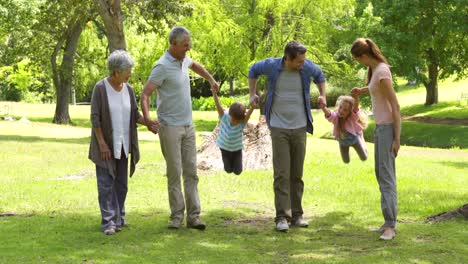 Familia-Multigeneracional-Sonriendo-Y-Tomados-De-La-Mano-En-Un-Parque