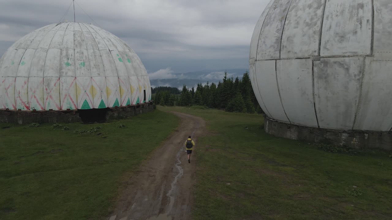 Person Hiking towards Abandoned Radar Domes in the Mountains