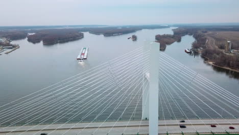 Antenne-Eines-Kohlelastkahns,-Der-Von-Einem-Schlepper-Geschoben-Wurde,-Der-Den-Mississippi-In-Der-Nähe-Von-Burlington-Iowa-Mit-Hängebrücke-Vordergrund-2-Hochfährt