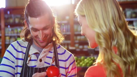 male staff assisting woman in selecting fresh vegetables