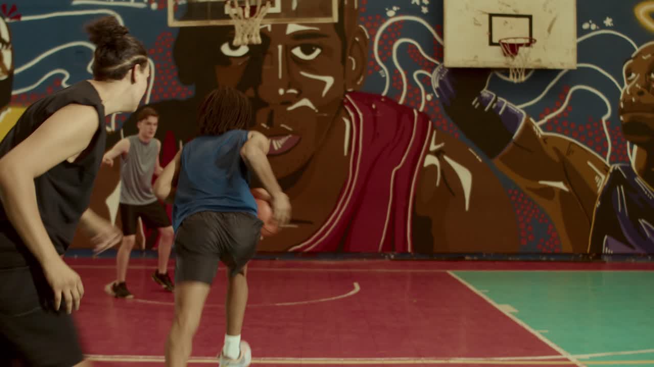 Young men playing basketball on a vibrant court with a mural
