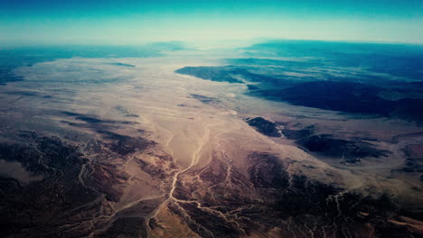 high altitude aerial flying over an arid desert landscape