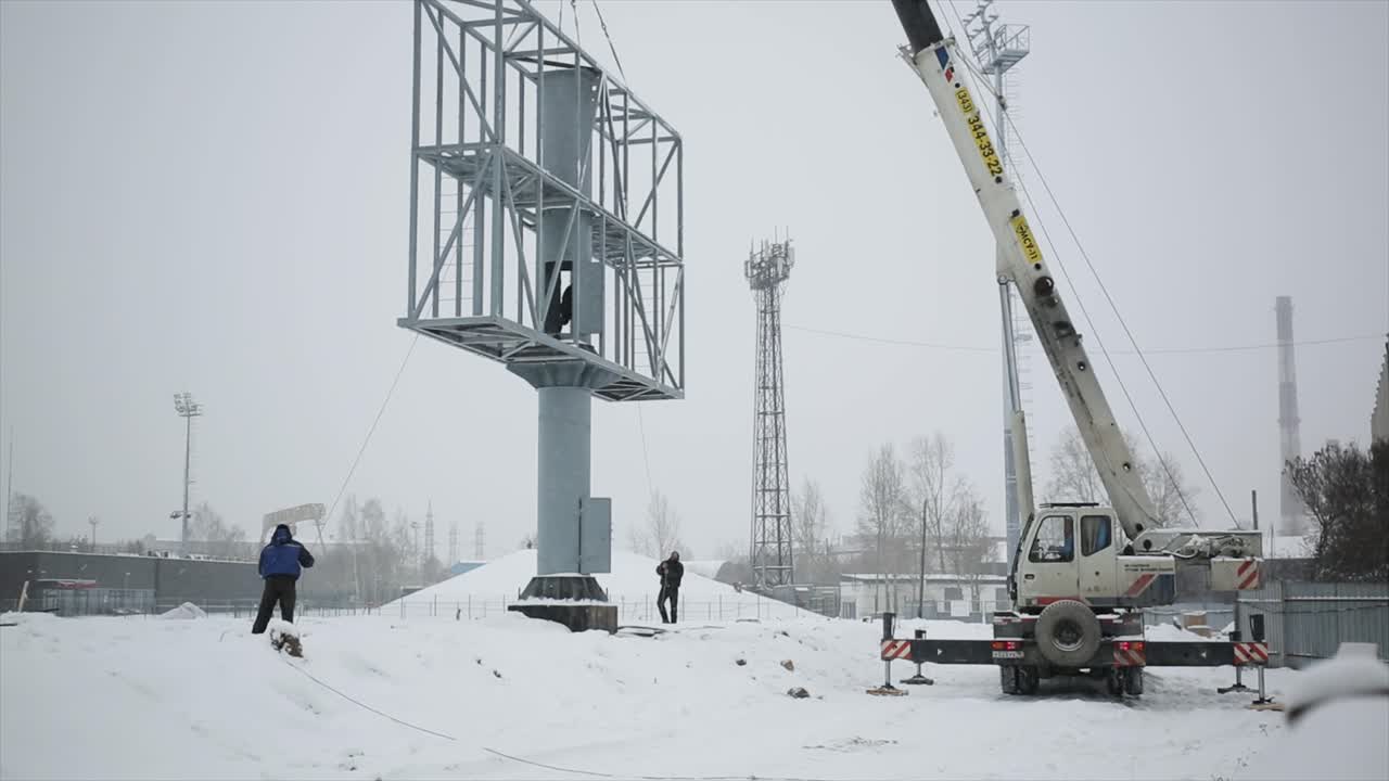 크레인으로 눈이 많이 내리는 곳에서 큰 광고판을 설치하는 것