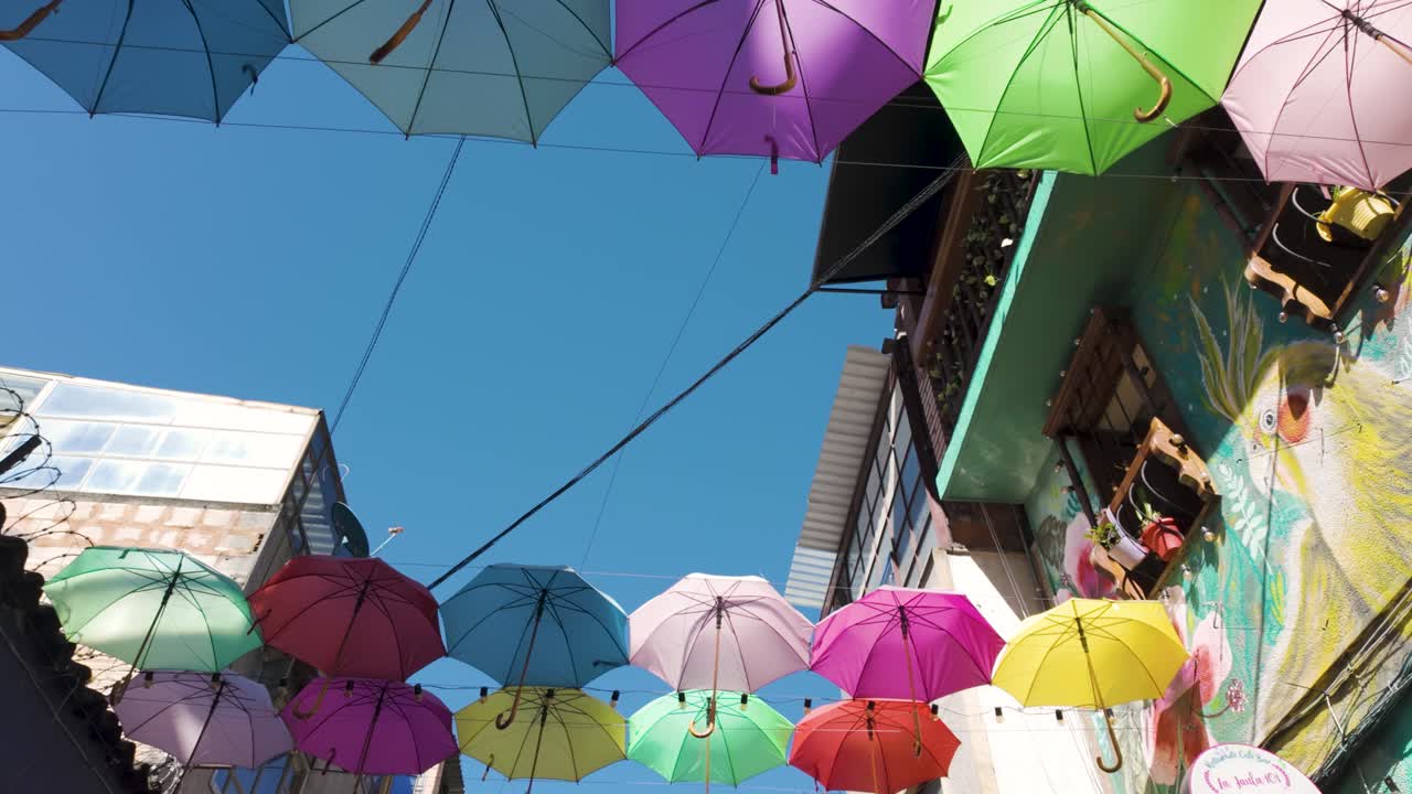 은 바고타의 라 캔델라리아의 거리에서 다채로운 우산 아래에서 고 있습니다.