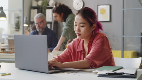 Young-Female-Trainee-Working-on-Laptop-at-Office-Desk