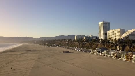 Car-tracks-in-the-sand,-beach-villas-large-hotels