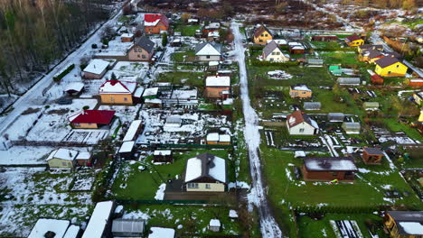 aerial drone fly above town of low houses, neighborhood, snowed roads, gardens