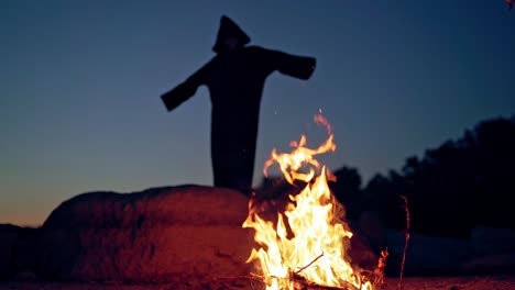 witch by night fire in forest. witch silhouette hexing in dark forest