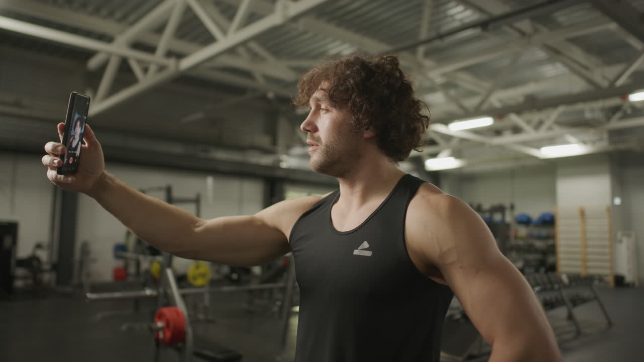 Male Athlete Filming Himself with Smartphone for Fitness Vlog in Gym