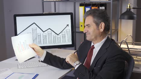 successful businessman analyzes financial charts and is happy.