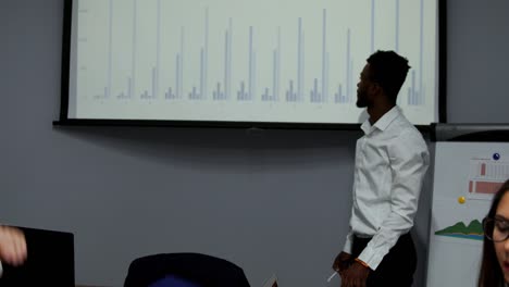el entrenador afroamericano da una presentación corporativa para los empresarios en la oficina, el empresario de piel oscura presenta un nuevo plan de negocios en la pizarra, hablando con los clientes escuchando al orador en la reunión