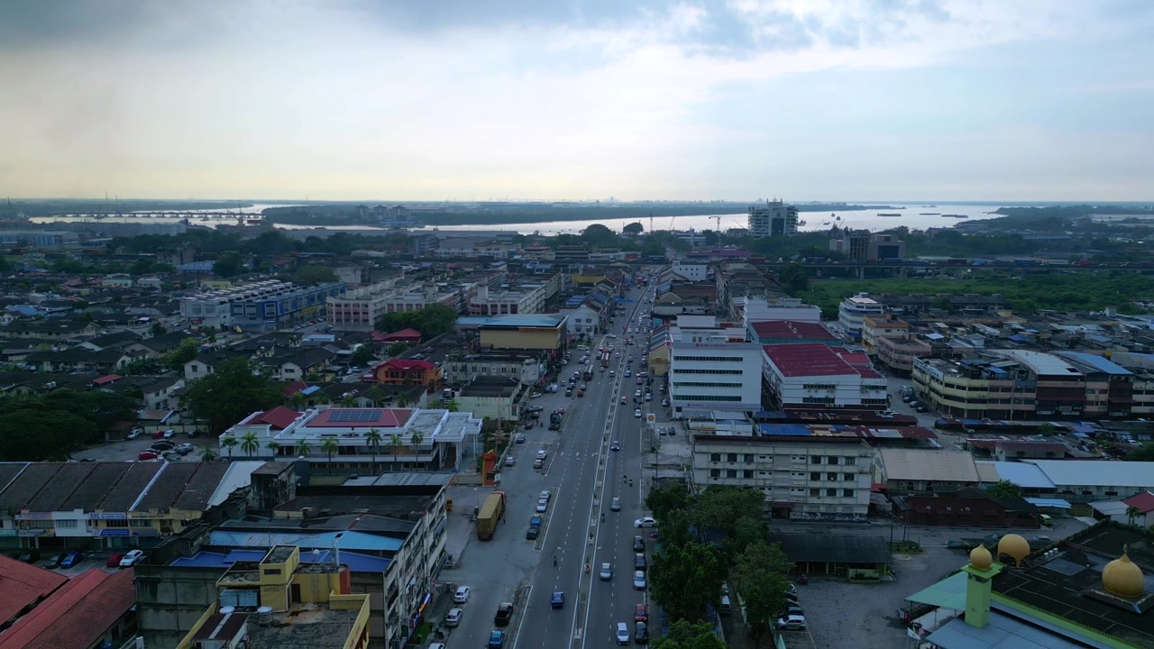 La strada principale a Port Klang, Malesia, con il traffico quotidiano in corso e gli edifici urbani circostanti al tramonto. Ottima vista aerea, panorama statico da drone in hovering