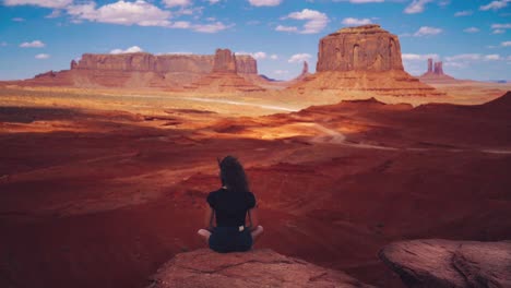 Beautiful and scenic Cinemagraph - seamless video loop of a young brunette model woman looking at the famous red Monument Valley landmarks in Utah, USA. her hair is moving in the wind.
