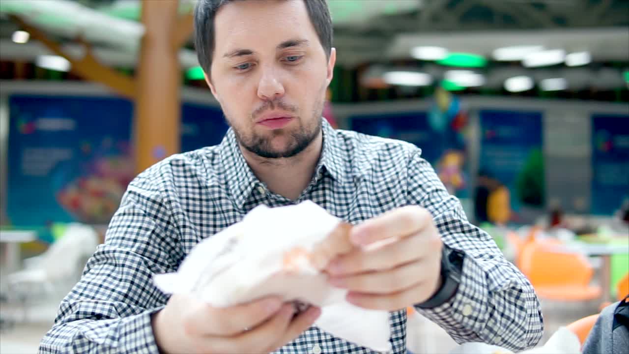 Man eating a hamburger in a food court