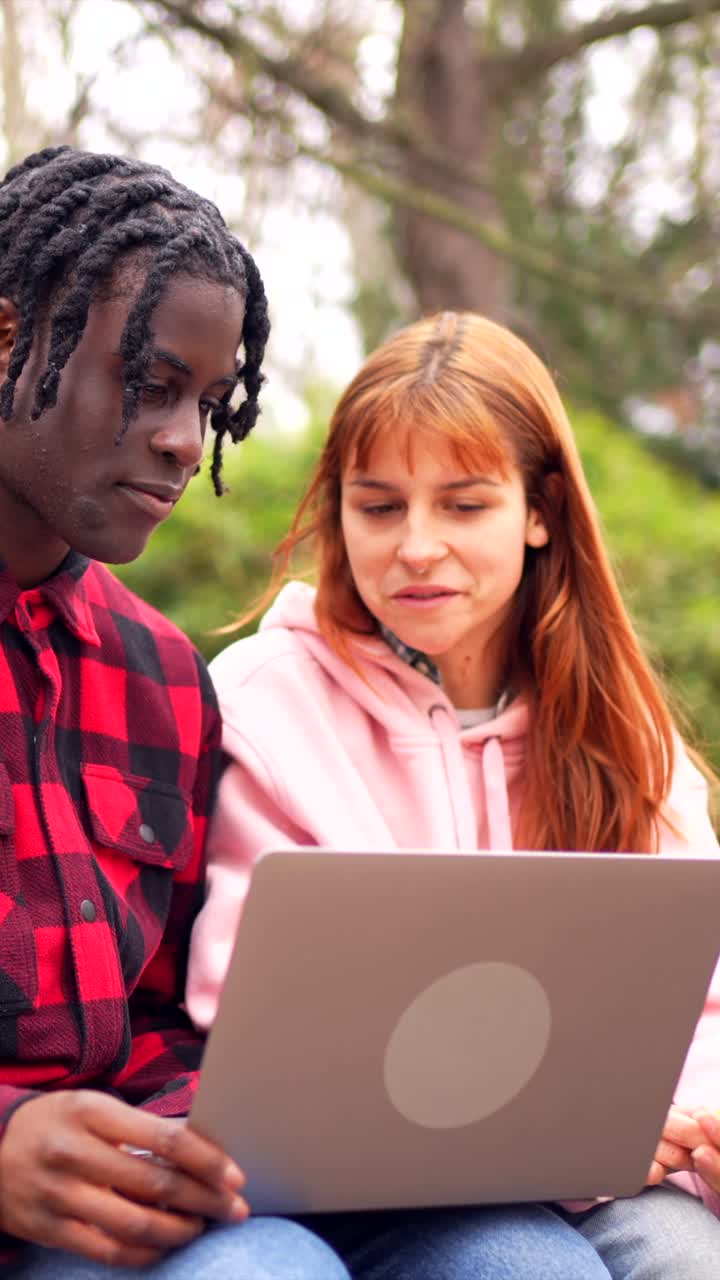 Young adults using a laptop outdoors