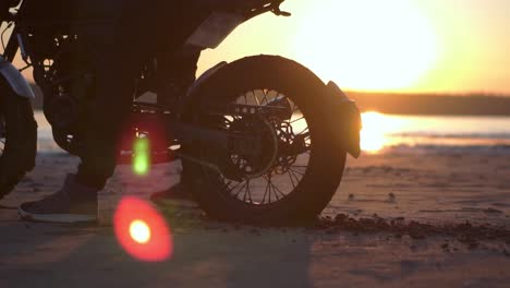 Biker-thrusts-on-the-spot-with-the-rear-wheel,-splashing-dirt-ground