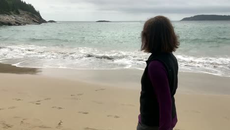 4k senior walking down sand beach at acadia national park in maine