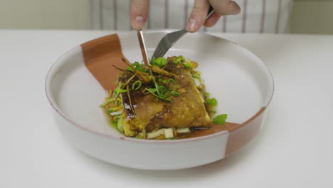 cutting exquisite egg and abalone dish with knife inside a plate