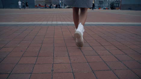 Woman-going-city-square-at-late-evening-in-urban-background.