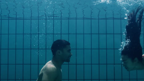 pareja romántica besándose bajo el agua en la piscina jóvenes enamorados disfrutando de un beso íntimo amantes sumergidos en el agua flotando con burbujas en una intimidad apasionada