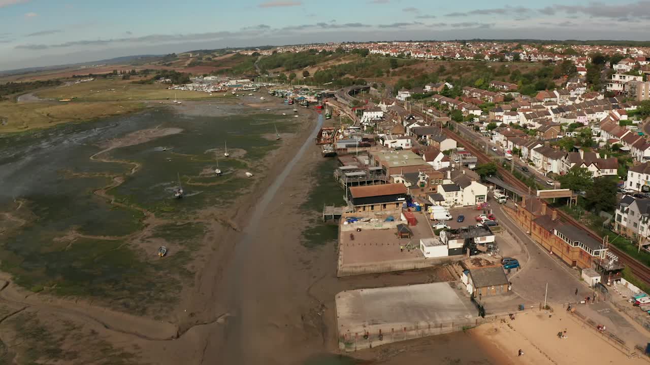 vuelo suave sobre muelles comerciales y vías de tren, pueblo pesquero costero sobre marismas.