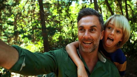 father and son taking a selfie on mobile phone in the park