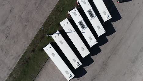 drone eye's bird top down view of line of public white bus parking in a station in the city center of an european capital