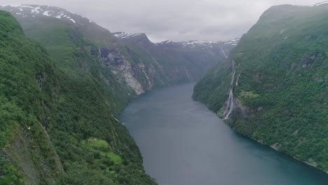 toma aérea en cámara lenta del fiordo de geiranger con la cascada de siete hermanas en el fondo durante el tiempo nublado