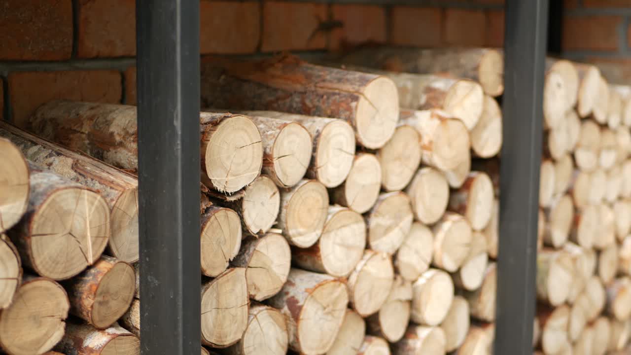 деревянные бревна, помещенные рядом с кирпичной стеной. сушеные дрова готовы к использованию на фоне красной кирпичной стенки