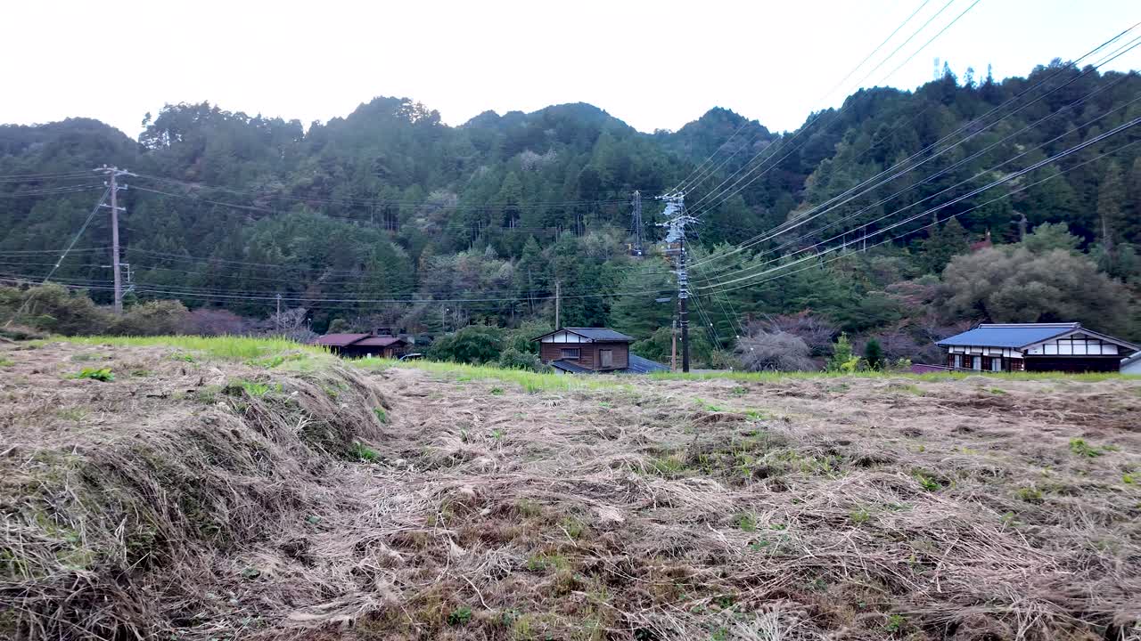 Mowed grassland overlooking traditional japanese houses in Tsumago juku, a post town in Nagiso, Japan, surrounded by forested hills