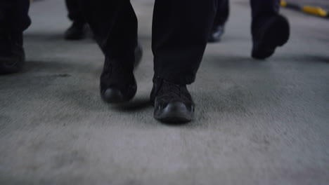 special forces team feet moving towards camera on road. men wearing black shoes