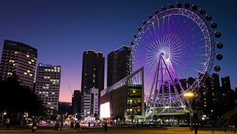 vibrant night sokcho cityscape with majestic sokcho eye ferris wheel illuminated. street is bustling with people activity walking along the sidewalks. skyscrapers and buildings towers in background