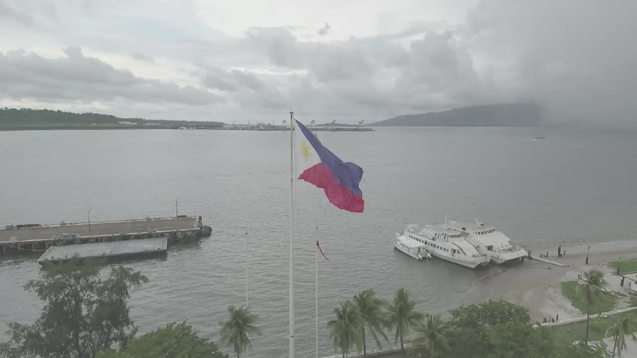 The Philippine flag flutters gracefully in the breeze, colors vibrant against the sky, each ripple and fold telling a story of pride and heritage, capturing attention with its rhythmic dance.
