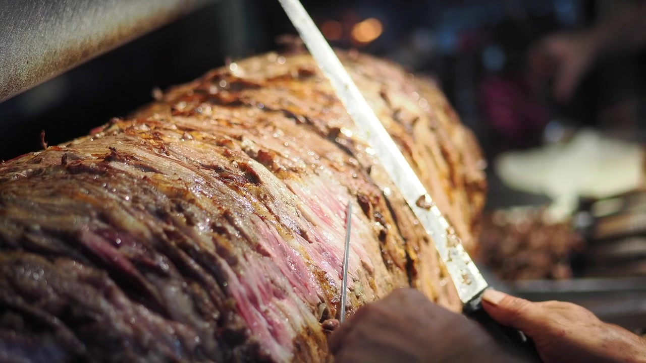 Chef che affetta carne tradizionale per doner kebab su spiedo verticale