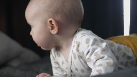 blue-eyed caucasian baby girl moves around in bed, close up