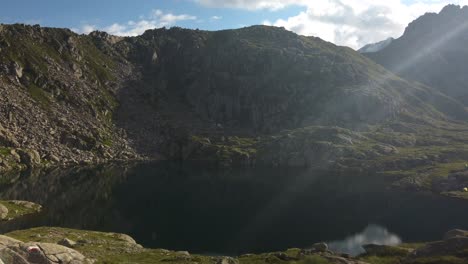 reflejo escénico de la montaña verde y rocosa en un pequeño lago en italia