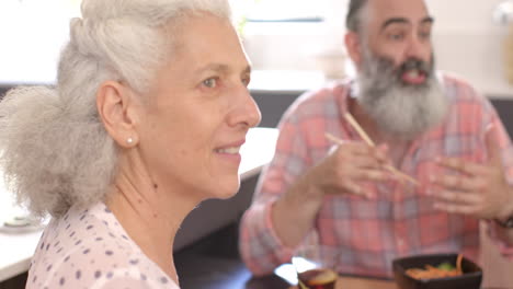 smiling senior woman enjoying time with friend at home, sharing meal