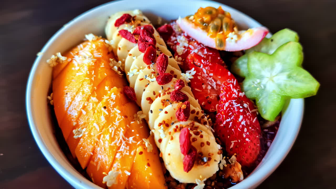 Fresh tropical fruit bowl with banana, passionfruit, starfruit, and goji berries