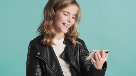 Teenage-Caucasian-girl-in-leather-jacket-watching-videos-and-laughing-on-her-smartphone.