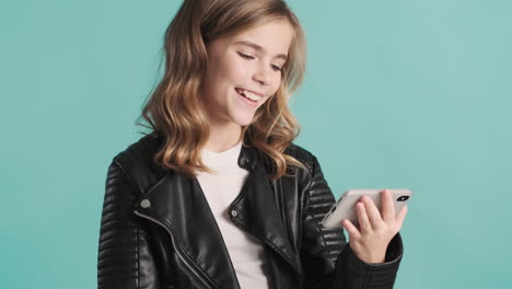 teenage caucasian girl in leather jacket watching videos and laughing on her smartphone.