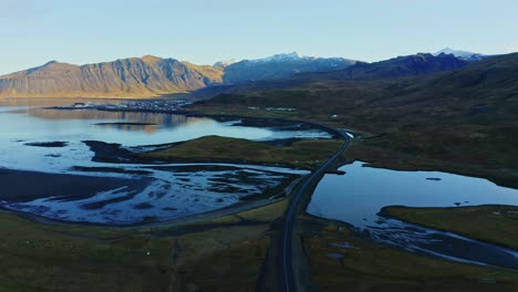 impresionante vista aérea de la hermosa carretera islandesa que serpentea junto al lago con un majestuoso fondo montañoso, islandia