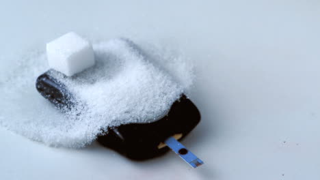 cubo de azúcar cayendo sobre una pila de azúcar en el monitor de glucosa en la sangre