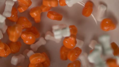 orange skulls and bones shaped candy slowly falling on a plate