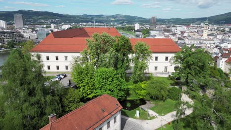 soaring drone view of linz’s schlossmuseum on the danube river, capturing the dynamic mix of historic architecture and flowing waters in austria’s vibrant cityscape