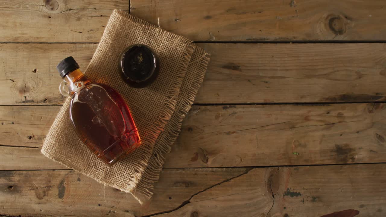 video de jarabe de arce en botella y tela en superficie de madera