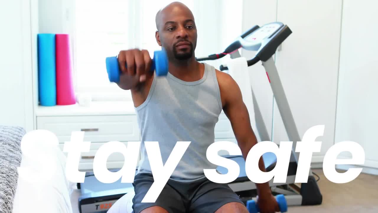 Stay safe text against african american man working out with dumbbells at home